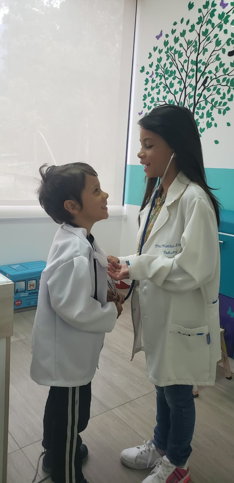 Dos niños jugando con un estetoscopio en el consultorio
